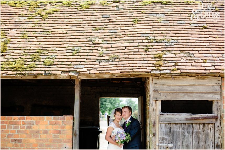 Natural wedding photograph of bride and groom in old green barn in Newdigate holding wildflower boutquet