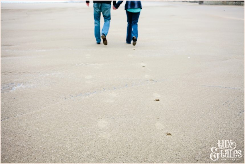 couple leaving footprints int he sand on beach