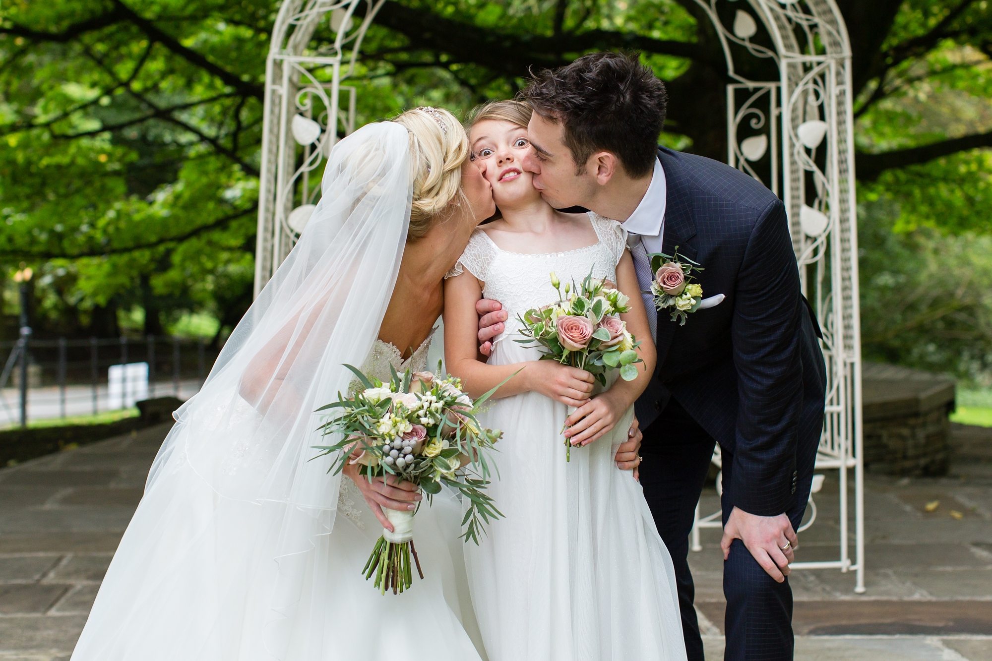 Funny photo of bride & groom kissing daughter