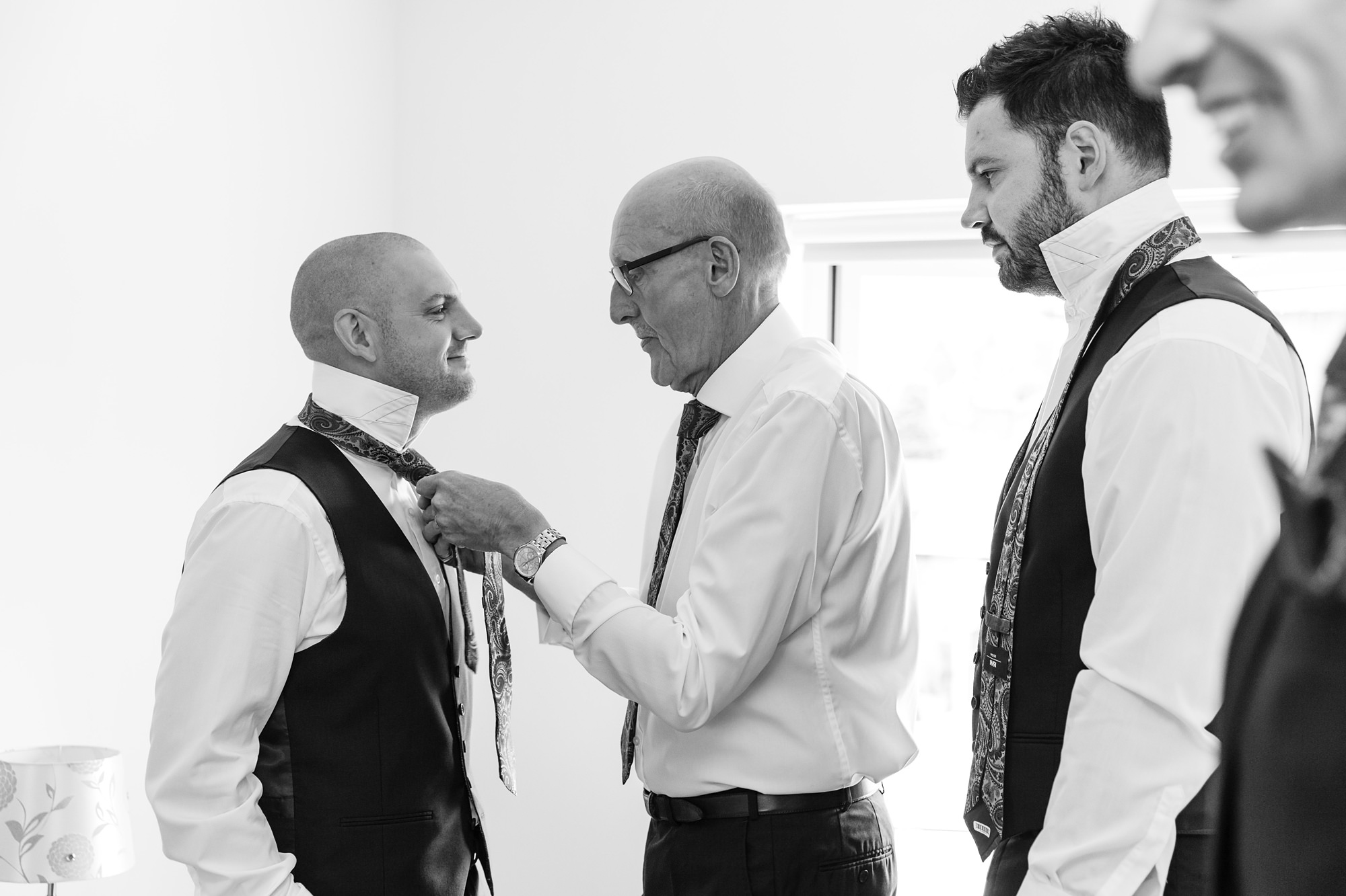 Groom prep ties being tied by dad