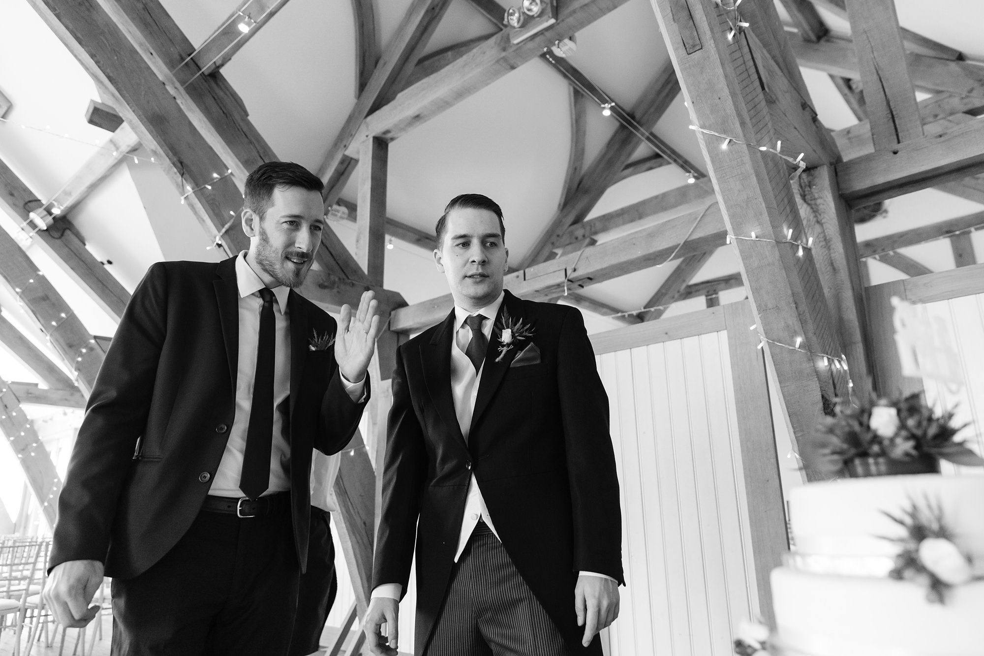 Groom and best man look at cake