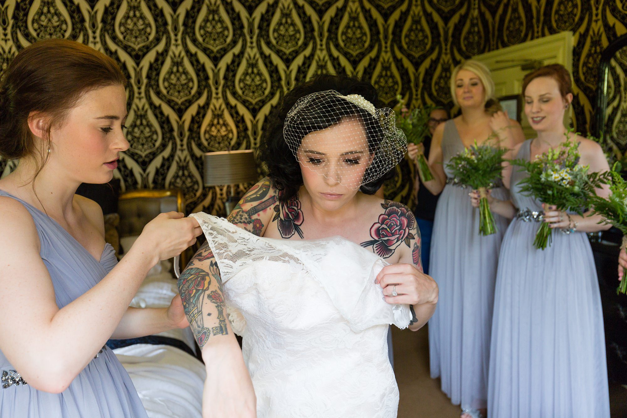 Bride gets into dress with tattoos on her shoulders