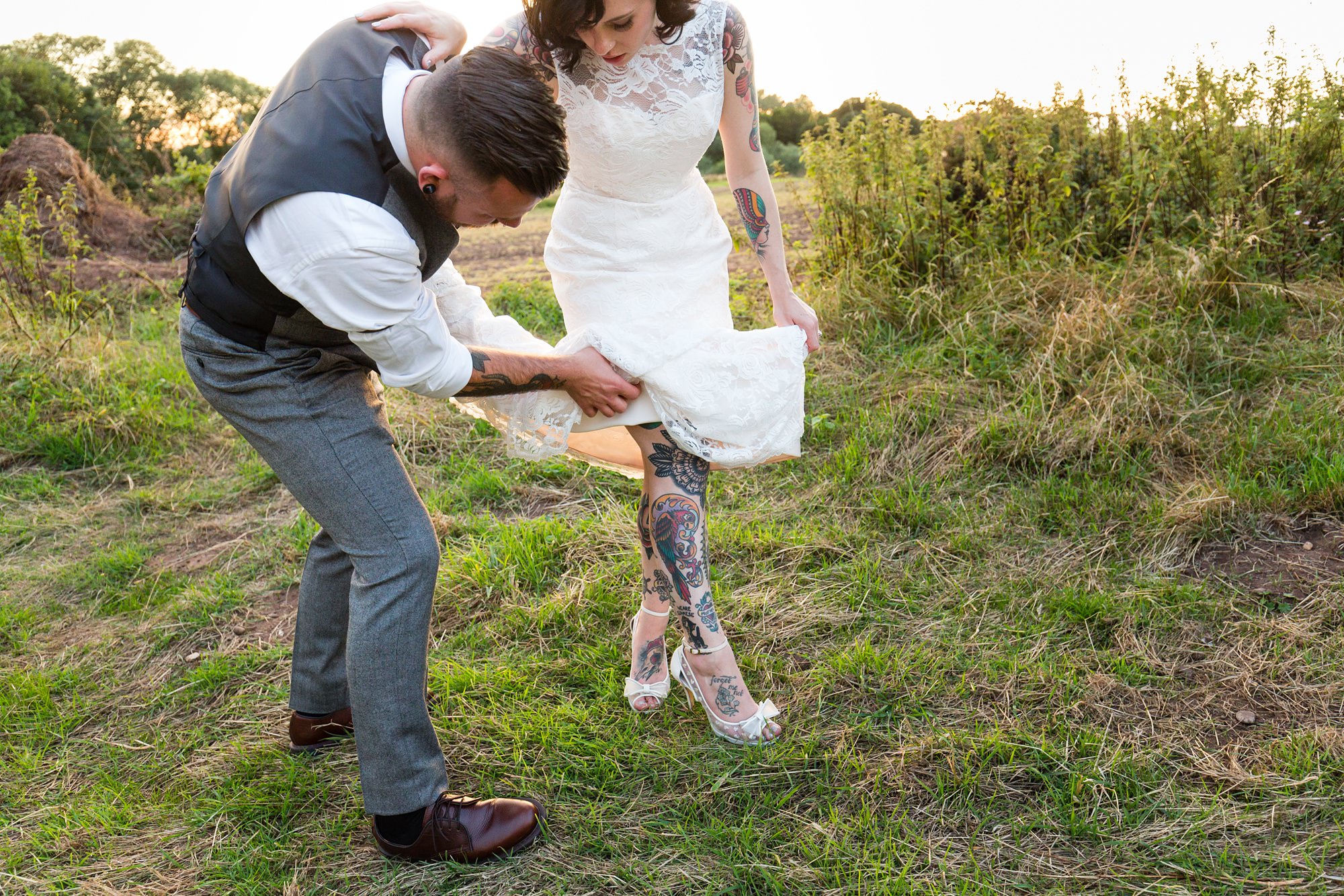Tattooed groom helps bride sort out her dress tattooed legs