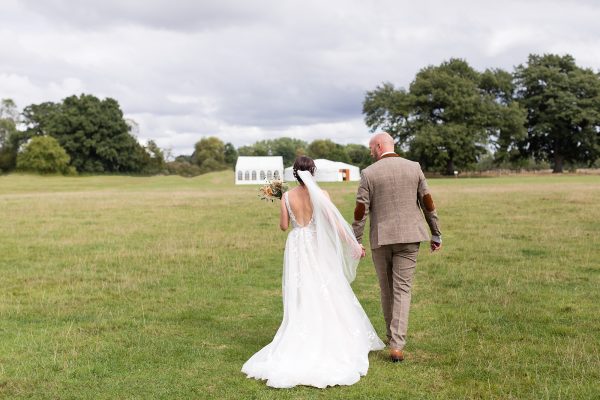 Bride & groom walk towards marquee at Escrick Park Wedding