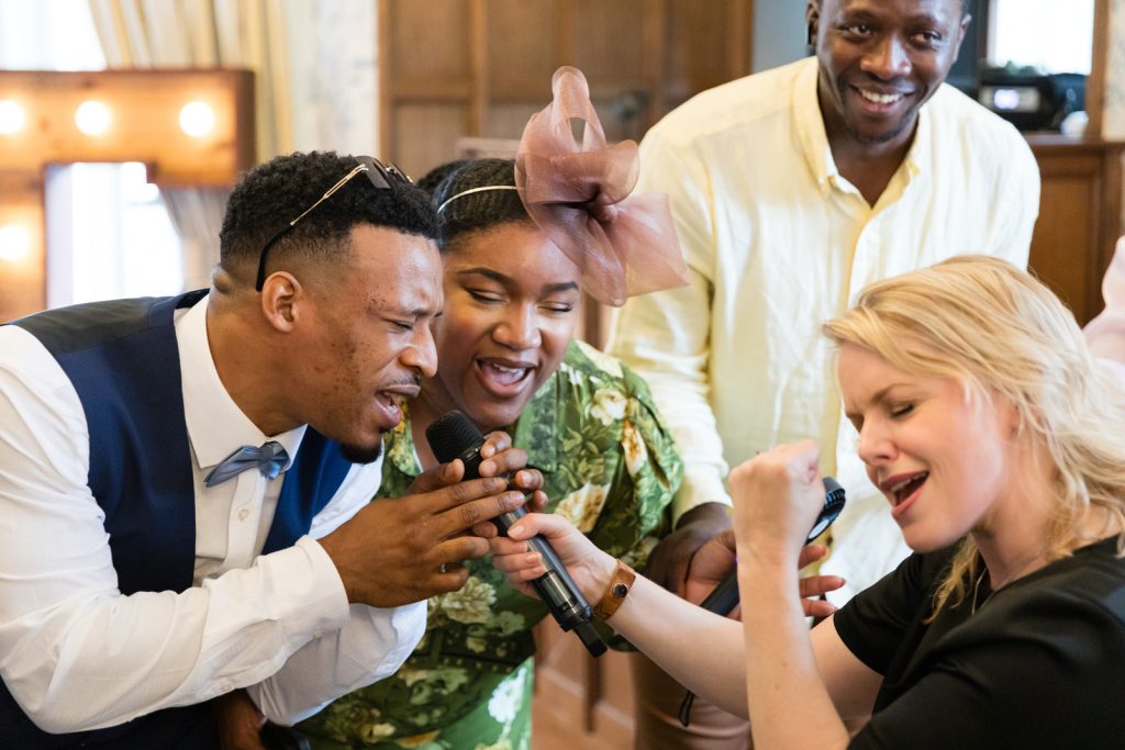 Guests sing into the microphone as performer pumps fist during entertainment at Rushpool hall wedding