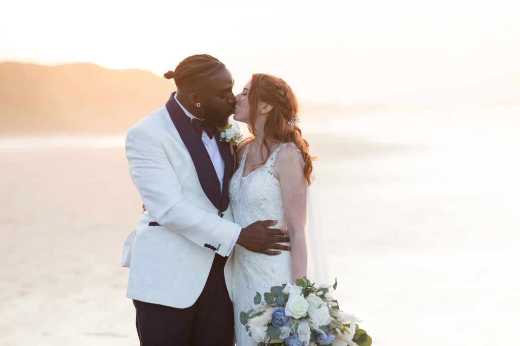 Groom kisses bride romantically in the sunset on the beach in Saltburn