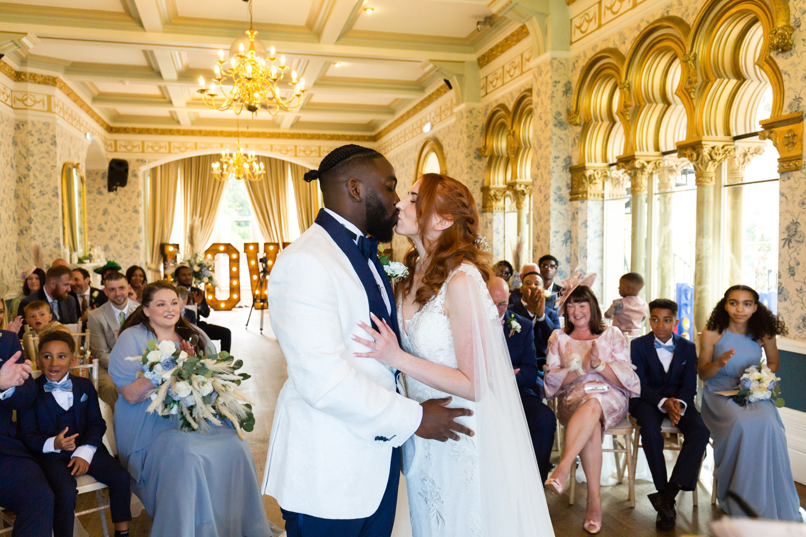 Bride and groom kiss at Rushpool Hall wedding with light up love letters behind them.